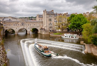 A boat on the River Avon near the weir and bridge - you can take a trip on a boat on your weekend in Bath