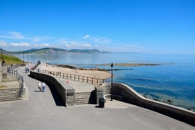 The pedestrianised Gun Cliff Walk in Lyme regis and the view out the sea. There are cliffs in the background