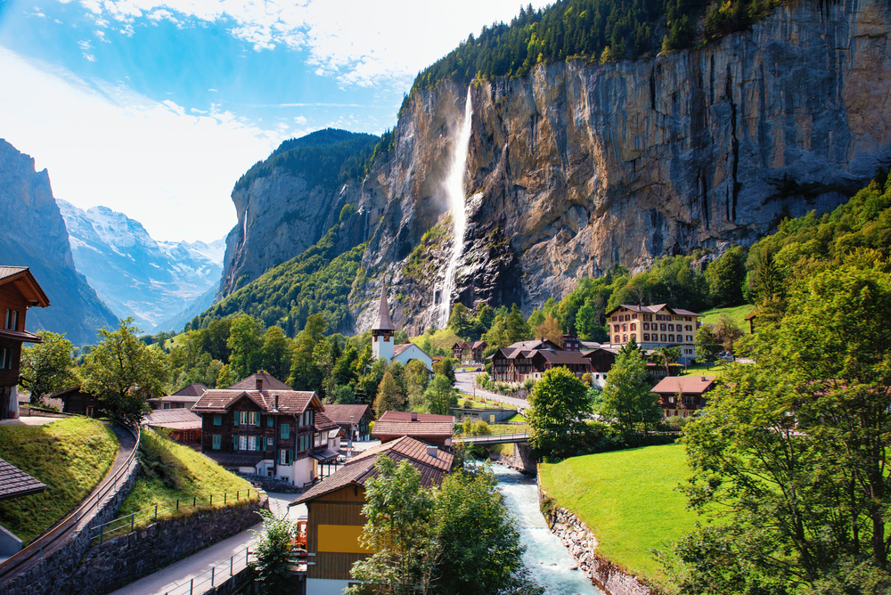 Lauterbrunnen with its chalet houses in a valley and a waterfall plunging down from the rocks - see this on a day trip from Bern