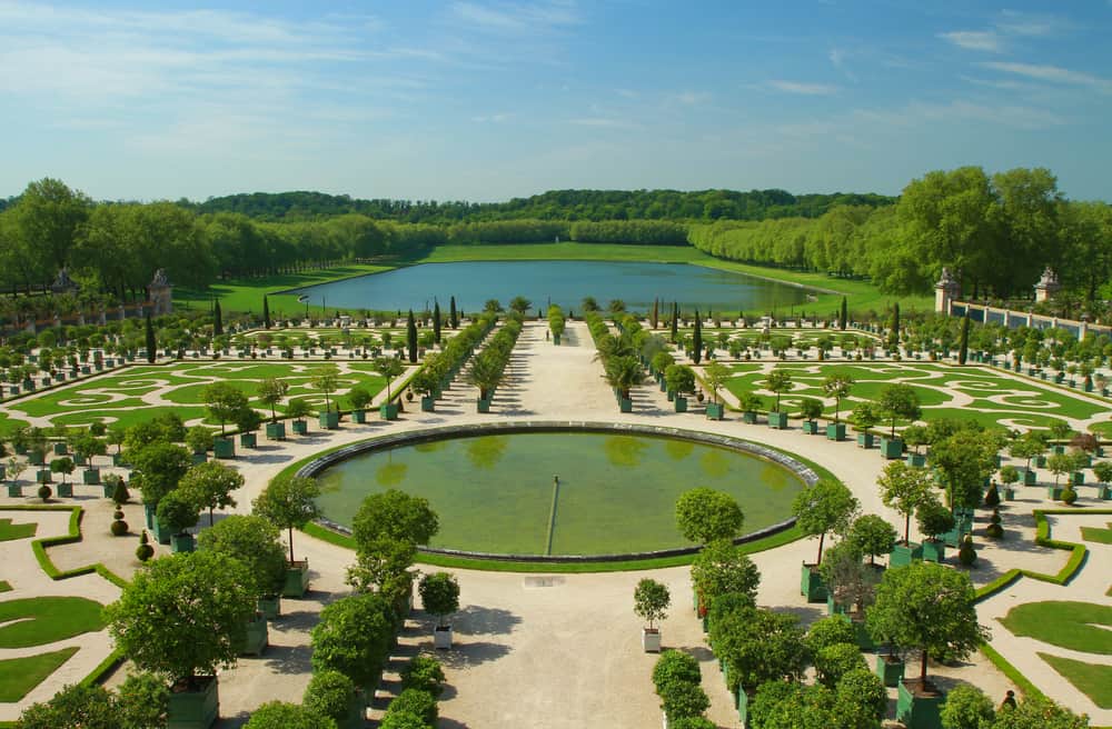 Part of the gardens in Versailles with formal lawns and a small lake - see this on a day trip to Versailles from Paris