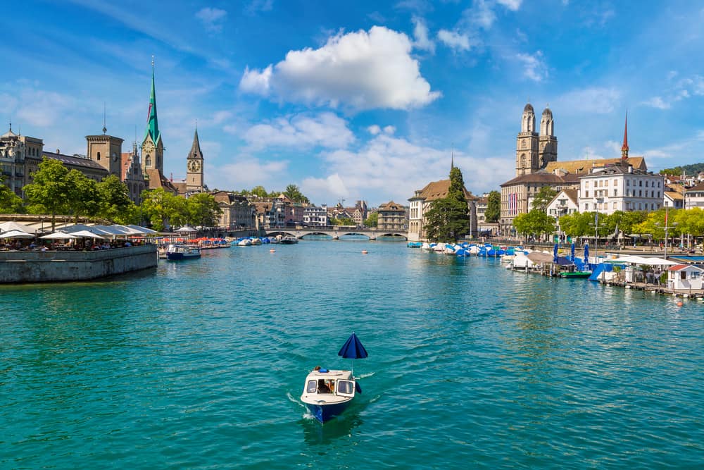 The Limmat River in Zurich with a boat sailing on it and the old town on either side 