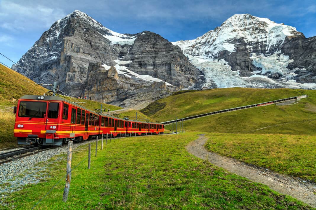 A red train with mountains in the background
