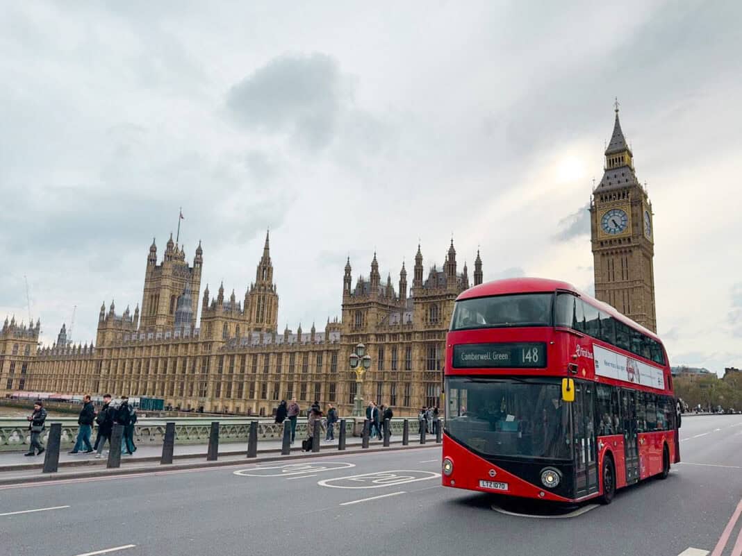 An image of part of the Houses of Parliament and Big Ben with a red double decker bus in front on the bridge